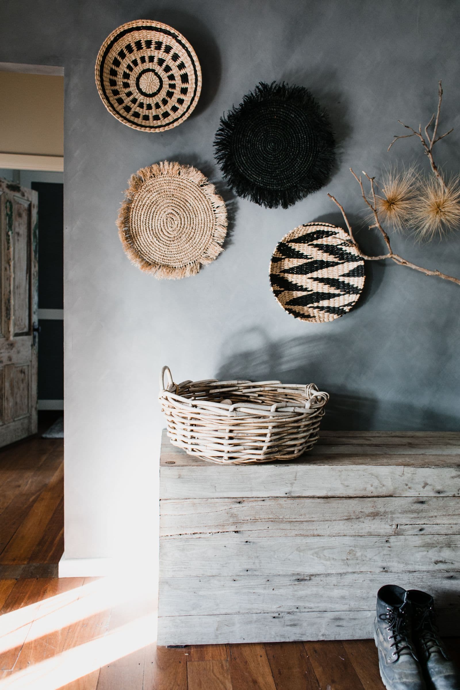 A styled interior with handwoven wall baskets and a rattan basket