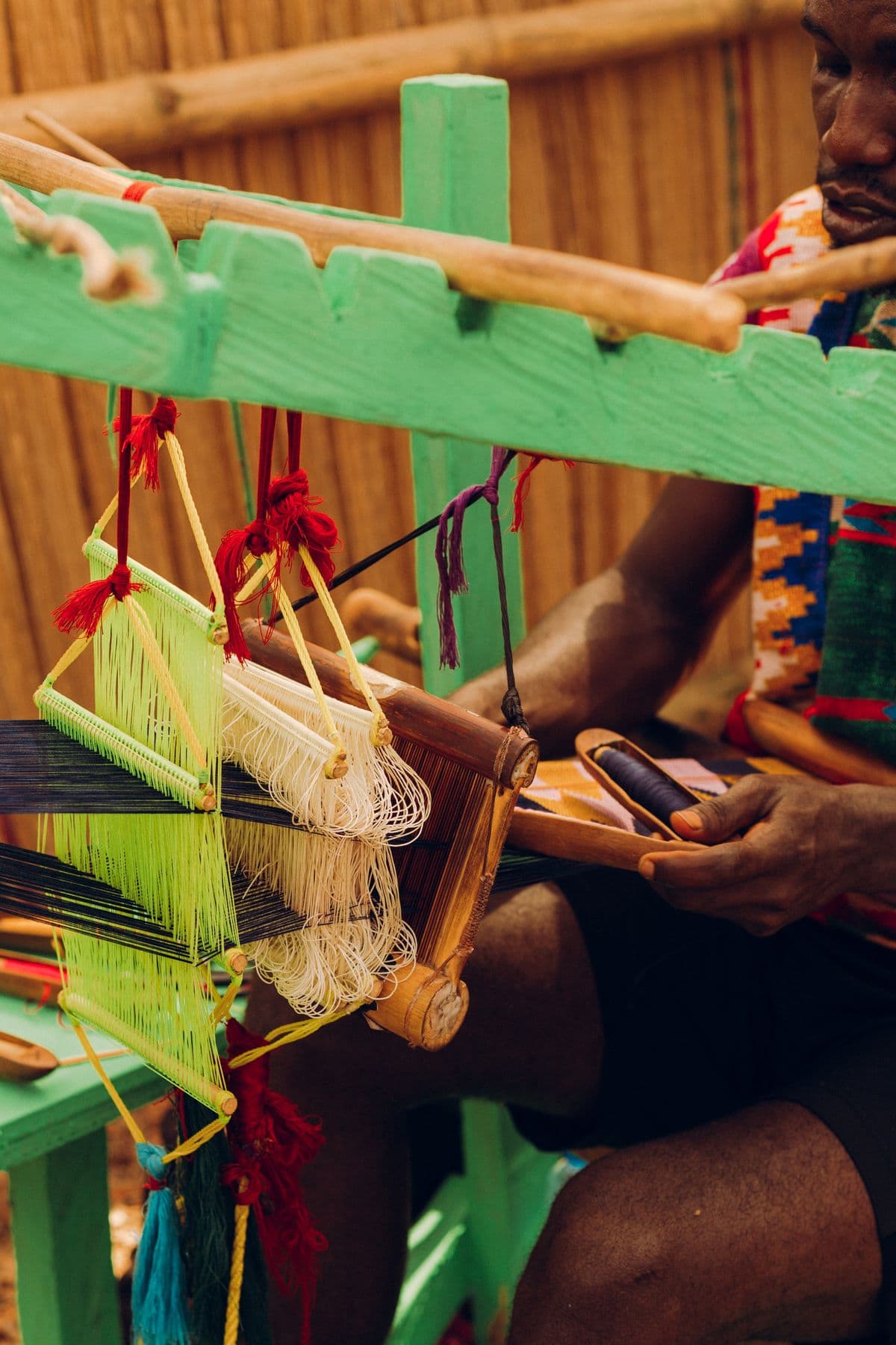 A weaver working colored threads on a traditional loom